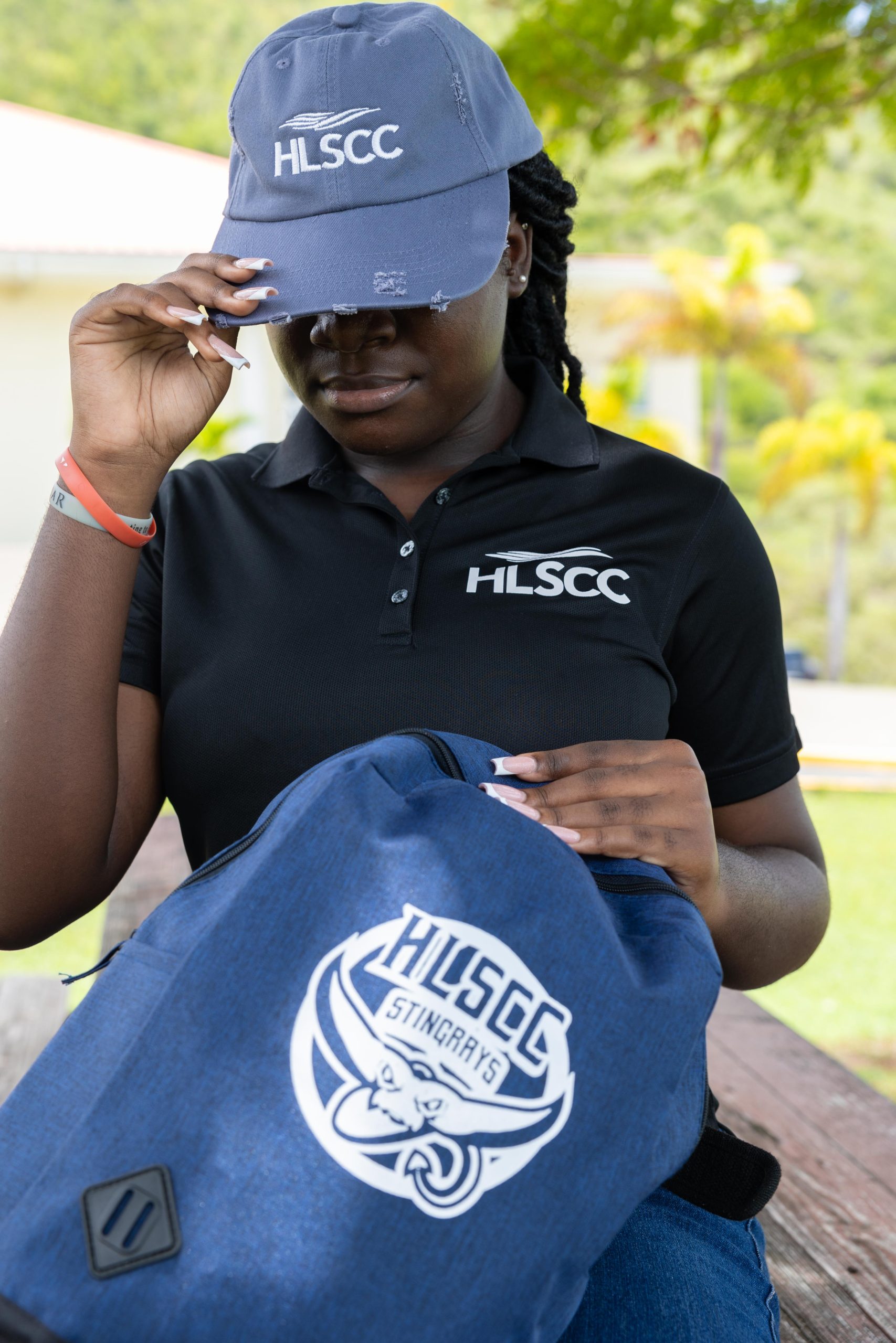 Student wearing HLSCC cap and holding campus backpack